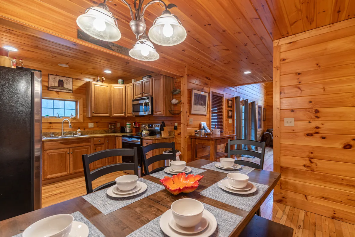 The image captures an open-concept dining and kitchen area, with a large dining table, modern kitchen fixtures, and warm lighting. The space is set up for group meals, celebrations, and shared time, illustrating how communal areas can bring families and friends together.