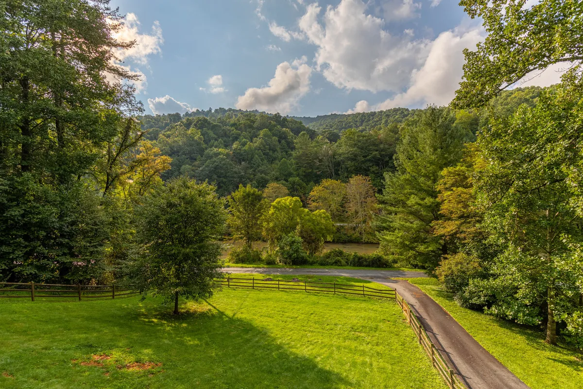 A scenic exterior view featuring rolling hills, lush greenery, a winding road leading into the landscape, and a cloudy sky overhead. The perspective suggests the ease of access to the outdoors, with an inviting road perfect for strolls or heading toward adventure.