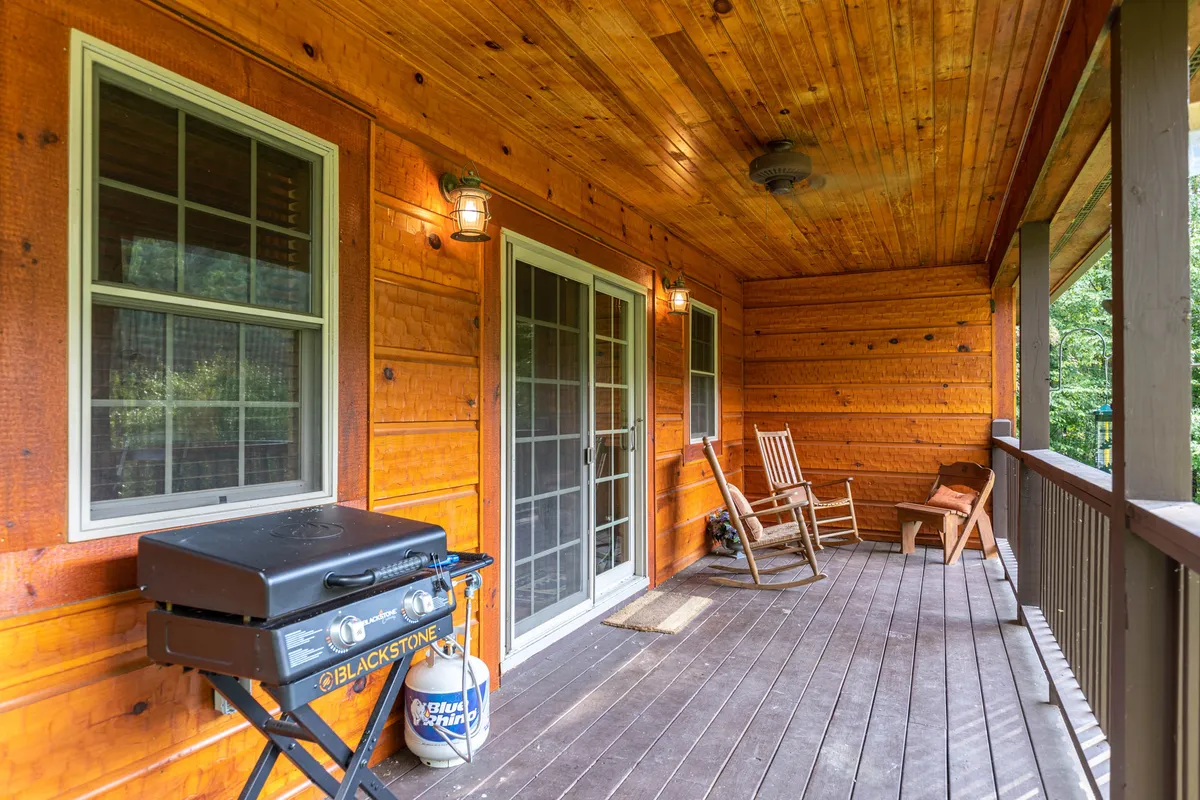 A covered porch with wooden rocking chairs, a grill, and glass doors leading inside. The porch blends indoor comfort with outdoor enjoyment, offering a relaxing spot to take in views or socialize with loved ones.